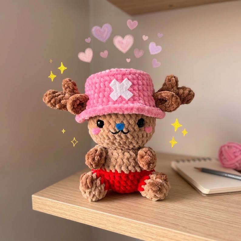 May include: A handmade plush toy of a cartoon character, featuring a pink hat with a white cross, brown antlers, and red shorts. The toy is sitting on a wooden shelf, with hearts and sparkles in the background.