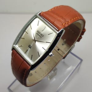 Reloj Seiko Tank vintage: caja rectangular chapada en oro, esfera plateada, movimiento de cuarzo japonés.