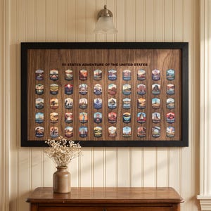May include: A rectangular wooden wall plaque with a black frame featuring the text 50 STATES ADVENTURE OF THE UNITED STATES. It displays fifty individual hexagonal illustrations, each representing a different U.S. state with unique landmarks.