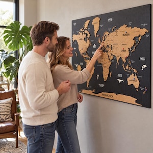 May include: A large rectangular wall-mounted world map featuring laser-cut wooden continents in a natural tan finish mounted on a solid black board. The map includes engraved country names, ocean labels, and decorative white silhouettes of marine life.