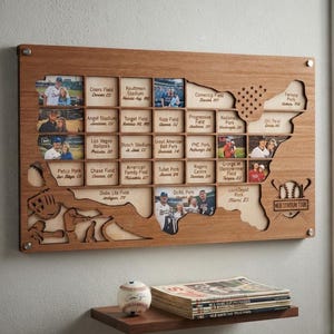 May include: A rectangular wooden wall display shaped like the United States map, featuring grid slots for photos and text labels of baseball stadiums. The design includes laser-cut baseball icons and the text MLB STADIUM TOUR in the bottom right.