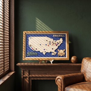 May include: A framed wooden map of the United States featuring a blue background, with the text BASEBALL MAJOR LEAGUE and Athletics. The map includes circular cutouts and a baseball icon with the text LESLIE AND SCOTT'S BASEBALL STADIUM TOUR.