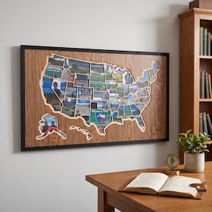 Puede incluir: Un expositor de pared rectangular de madera con un mapa recortado de los Estados Unidos. El mapa está dividido en secciones con forma de estado, cada una con una fotografía. El tablero tiene un marco negro y está sujeto con pernos de metal.