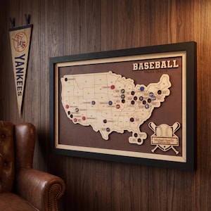 May include: A framed wooden map of the United States featuring the text BASEBALL MAJOR LEAGUE and Michael Family Stadium Map. The map includes cutouts for bottle caps, with several colorful caps inserted into various state locations.