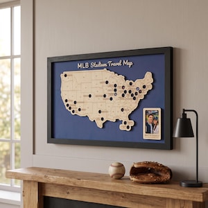 May include: A framed MLB Stadium Travel Map featuring a light wood cutout of the United States with circular cutouts for stadium locations, set against a dark blue background. A small rectangular photo frame labeled SMITH FAMILY is attached.