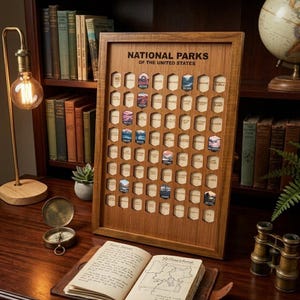 May include: A wooden National Parks of the United States display board featuring a grid of hexagonal cutouts, some filled with small park-themed tokens. The board is positioned on a desk with a journal, a compass, and a lamp nearby.