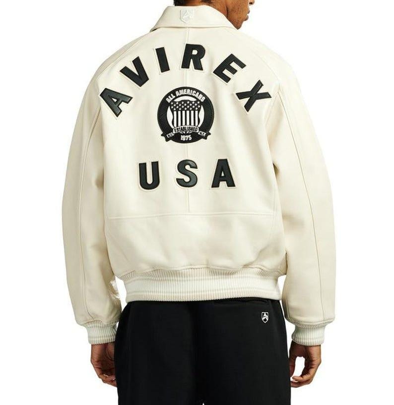 Back view of Avirex Jacket Men leather varsity style jacket featuring large “AVIREX USA” lettering and embroidered All Americans crest logo on the back. This bold Men Avirex Jackets design includes ribbed white striped cuffs and hem, premium leather construction, and classic bomber fit inspired by Avirex heritage style.