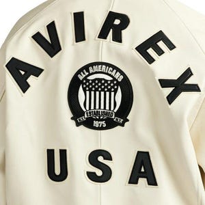 Back view of Avirex Jacket Men leather varsity style jacket featuring large “AVIREX USA” lettering and embroidered All Americans crest logo on the back. This bold Men Avirex Jackets design includes ribbed white striped cuffs and hem, premium leather construction, and classic bomber fit inspired by Avirex heritage style.