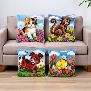 May include: Four decorative throw pillows with embroidered animal designs. The pillows feature a kitten, monkey, puppy, and chick, each set against a blue sky background with flowers. The pillows are on a beige sofa.