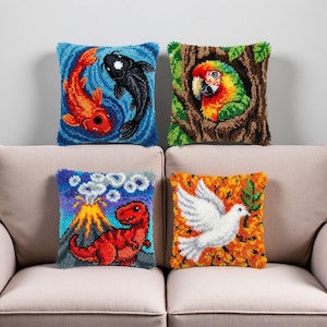 Könnte beinhalten: Vier dekorative Zierkissen mit farbenfrohen Designs. Eines zeigt Kois, ein anderes einen Papagei, ein drittes einen Dinosaurier und Vulkan, und das letzte eine weiße Taube mit einem Olivenzweig. Die Kissen sind quadratisch und haben eine strukturierte Optik.