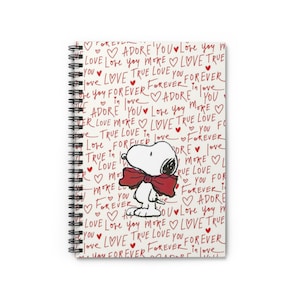 Puede incluir: Un cuaderno con espiral con Snoopy con una pajarita roja. La cubierta de color crema está cubierta de texto rojo escrito a mano, incluidas las palabras "Love", "Forever" y "Adore", junto con ilustraciones de corazones. El cuaderno está diseñado para escribir.