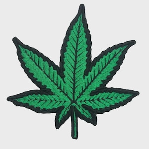 Könnte beinhalten: Ein grüner Cannabis-Blatt-Aufnäher mit schwarzem Rand. Der Aufnäher hat detaillierte Nähte, die die Adern des Blattes hervorheben. Ein klassisches Symbol, ideal zum Aufnähen auf Kleidung oder Accessoires.