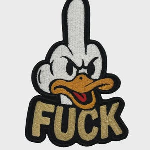 Könnte beinhalten: Gestickter Aufnäher mit einer Zeichentrickente, die den Mittelfinger zeigt. Die Ente hat einen weißen Kopf, schwarze Augen und einen orangen Schnabel. Das Wort "FUCK" ist in goldenen Buchstaben auf schwarzem Grund gestickt.