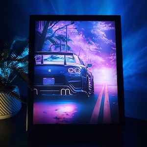 Op de afbeelding: Een ingelijste print met een blauwe sportwagen op een weg, tegen een paars en blauwe lucht. De achterlichten van de auto zijn zichtbaar en de scène heeft een neon-esthetiek. De print zit in een zwart frame.