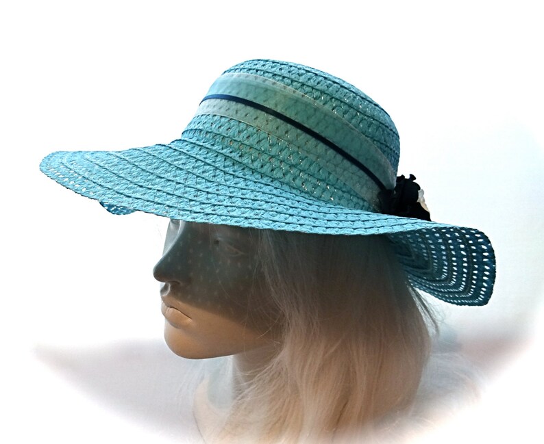 May include: A light blue straw sun hat with a wide brim and a black ribbon.