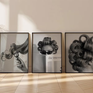 Op de afbeelding: Drie ingelijste zwart-wit prints. Eén toont een hand die een föhn vasthoudt met vloeiend haar. Een andere toont een persoon met een zonnebril en haarrollers, die een tijdschrift leest met de tekst "the imesse". De derde print toont een persoon met haarrollers.