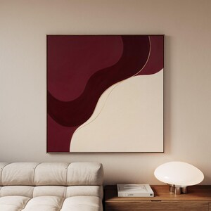May include: A square wall art piece featuring a deep burgundy and cream colour palette. The composition consists of two large, fluid, organic shapes separated by a thin, delicate gold line that curves diagonally across the canvas surface.