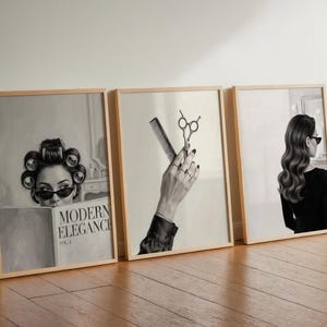May include: Three framed wall art prints in light wood frames. The first shows a person with hair rollers and sunglasses reading a book titled MODERN ELEGANCE VOL 4. The second shows a hand holding scissors and a comb. The third shows a person from behind.