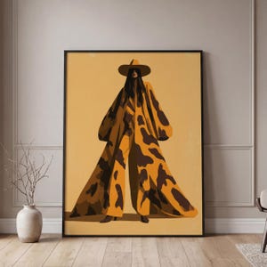 May include: A framed wall art print featuring a stylized illustration of a figure wearing a wide-brimmed hat and a long, flowing coat with a brown and mustard yellow cow-print pattern. The figure stands against a solid mustard yellow background.