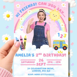 May include: A rectangular birthday invitation card featuring a pink background with a rainbow, clouds, daisies, a yellow sun, three crayons, and a yellow school bus. The text reads: HI FRIENDS! CAN YOU SAY... AMELIA'S 2ND BIRTHDAY! SATURDAY 26 SEPT 2PM - 4PM.