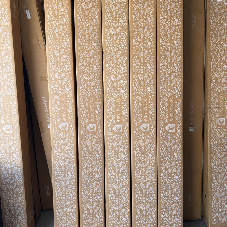 May include: A stack of cardboard boxes with a white floral pattern and the text "RUBY RYE CO" printed on them.