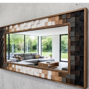 Puede incluir: Espejo rectangular con marco de madera y un patrón de mosaico de varios tonos de madera. El diseño del mosaico presenta una mezcla de bloques cuadrados marrón oscuro, gris, marrón claro y blanco. El espejo refleja un salón moderno con un sofá gris y una mesa de centro de madera.