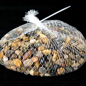 May include: A bag of mixed color pebbles in a white mesh bag. The pebbles are various shades of brown, tan, gray, and black.