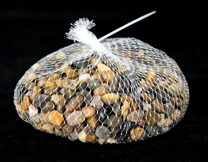May include: A bag of mixed color pebbles in a white mesh bag. The pebbles are various shades of brown, tan, gray, and black.