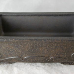 May include: A rectangular brown ceramic bonsai pot with a textured surface and decorative details around the rim and base.