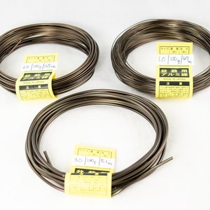 May include: Three spools of brown aluminum wire for bonsai trees. The spools are labeled with the wire thickness, weight, and length in metric units. The labels also say "Bonsai Use Aluminum Wire" and "Made in Japan".