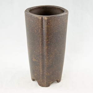 May include: A brown ceramic planter with a square shape and a textured surface. The planter has a wide opening and a base with four feet.