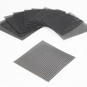 May include: A set of 11 black plastic mesh squares. The squares are arranged in a fan shape with one square lying flat in the foreground.