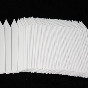 May include: A stack of 50 white plastic plant markers, each with a pointed top and a flat writing surface.