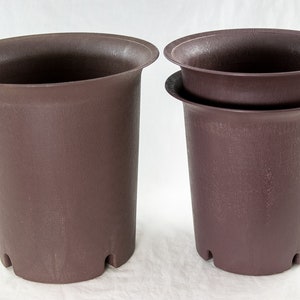 May include: Two brown plastic plant pots, one stacked on top of the other. The pots have a textured surface and a slightly flared lip.