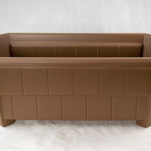 May include: A brown rectangular plastic planter with a wood-grain texture. The planter has a slightly flared top and bottom and sits on four small feet.