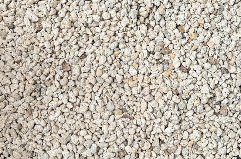May include: A close-up of a pile of small, white, and gray stones. The stones are smooth and rounded, and they are all about the same size.
