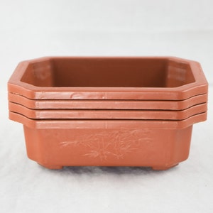 May include: A set of four terracotta bonsai pots with a bamboo design. The pots are stacked on top of each other.