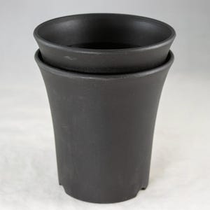 May include: Two black, tapered plant pots stacked together. The pots have a matte finish and a slightly flared rim. The pots are designed for indoor or outdoor use and are suitable for various plants.