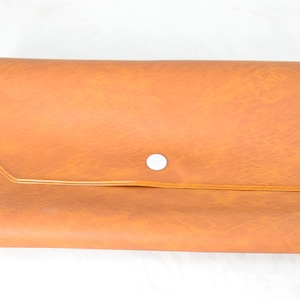 May include: A brown leather-like clutch with a white button closure.