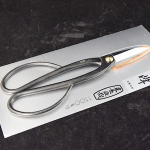 May include: Black pruning shears with a silver blade and a gold accent on the handle. The shears are on a silver background with Japanese text that reads "Zenkoku"