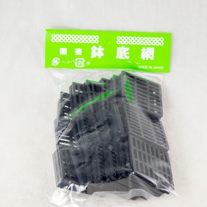 May include: A package of black plastic grate pieces, labeled "園芸 鉢 底 棚" in Japanese, which translates to "Gardening Pot Bottom Shelf", and "MADE IN JAPAN".