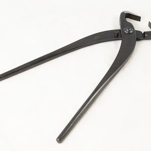 May include: Black metal pruning shears with a curved handle and a sharp blade. The shears are designed for cutting branches and stems.