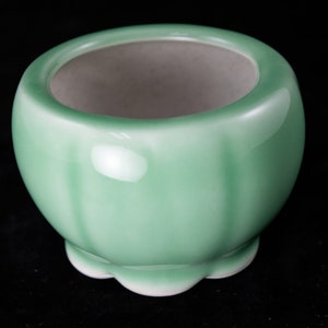 May include: A small, green ceramic planter with a scalloped rim and a smooth, glossy finish.