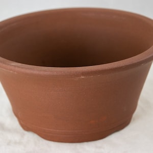 May include: A terracotta bonsai pot with a rounded shape and a slightly flared rim.