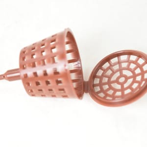 May include: A brown plastic plant root stimulator with a pointed end and a removable lid. The lid has a circular grid pattern.