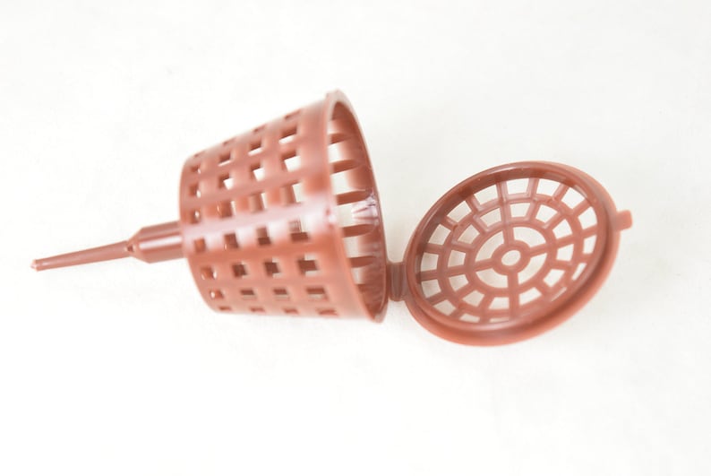 May include: A brown plastic plant root stimulator with a pointed end and a removable lid. The lid has a circular grid pattern.