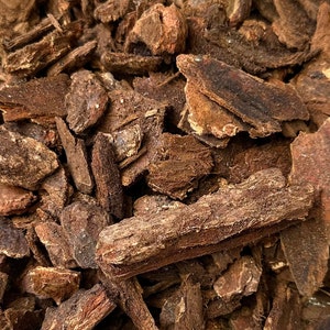 May include: Close-up of a pile of dried, brown, bark-like pieces. The pieces are irregularly shaped and have a rough texture.