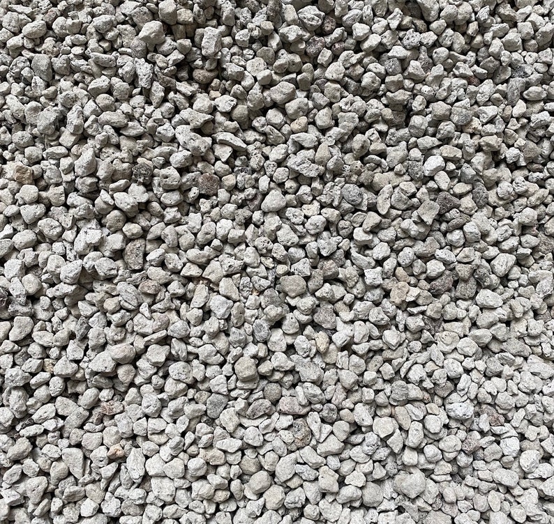 May include: A close-up view of a pile of small, white, and gray gravel. The gravel is a mix of different sizes and shapes, and it has a rough, textured surface.