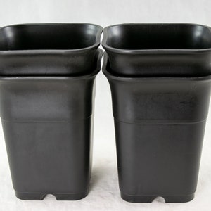 May include: Four black plastic square plant pots stacked in two pairs. The pots are empty and ready for planting.