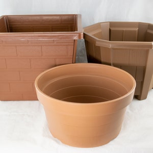 May include: Three terracotta-colored plastic planters of different shapes and sizes. The largest planter is rectangular with a brick-like texture. The medium-sized planter is round with a smooth surface. The smallest planter is octagonal with a wood-like texture.